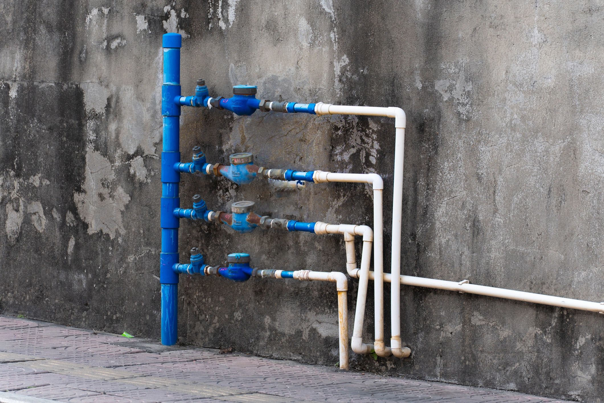 Plumbing pipes and meters mounted on an exterior wall